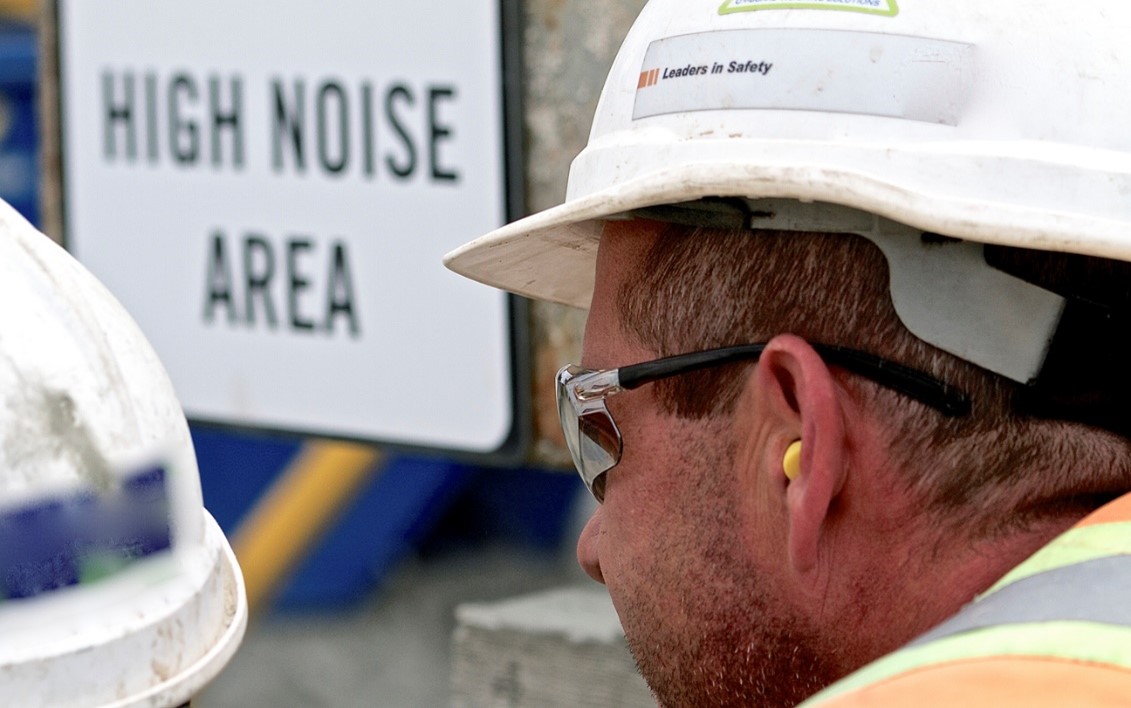 Man with disposable ear plugs and hardhat in high noise area